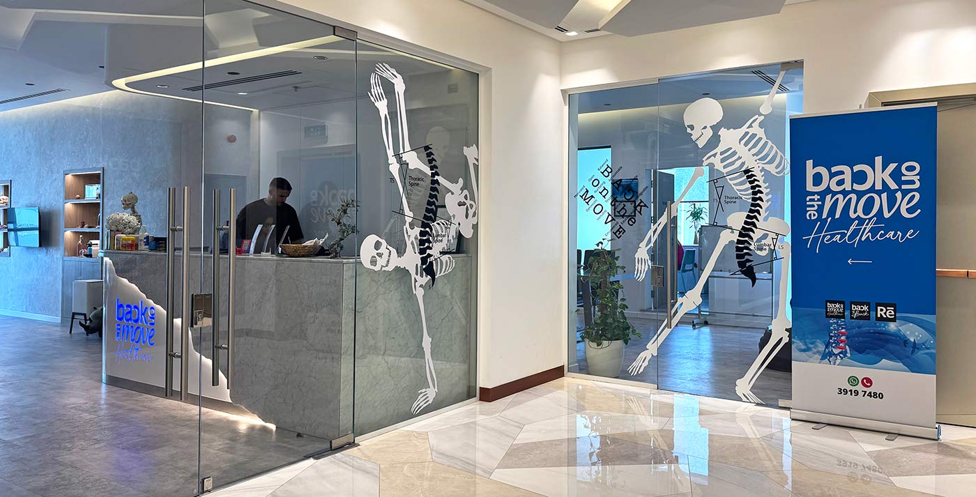 Clinical entrance and reception lobby of Back on the Move Healthcare featuring custom skeleton window graphics and corporate branding.