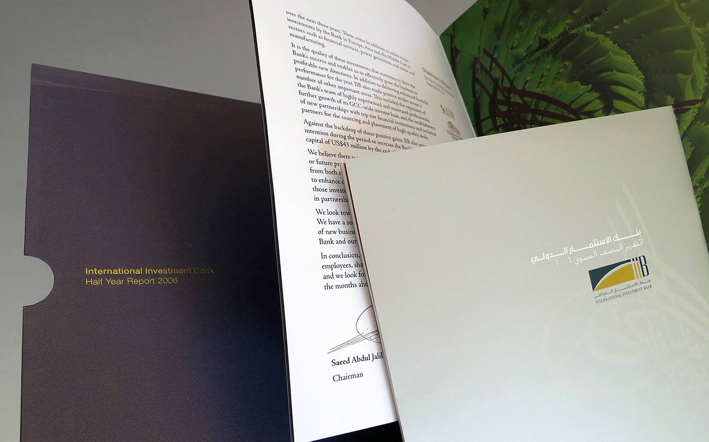 A presentation of the International Investment Bank Half Year Report 2006, featuring a dark blue outer folder, an open report page containing a letter signed by the Chairman, and a light-colored cover page with the bank's logo and Arabic text.