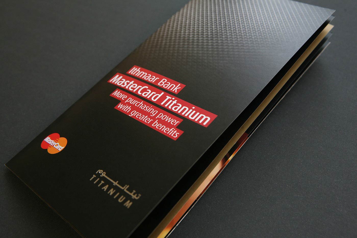 A marketing brochure for the Ithmaar Bank MasterCard Titanium credit card, featuring a textured black cover with red text labels and the MasterCard logo.