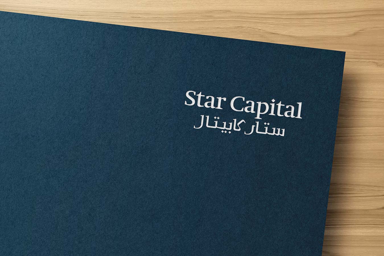 White bilingual Star Capital logo debossed on a textured dark navy blue paper background.
