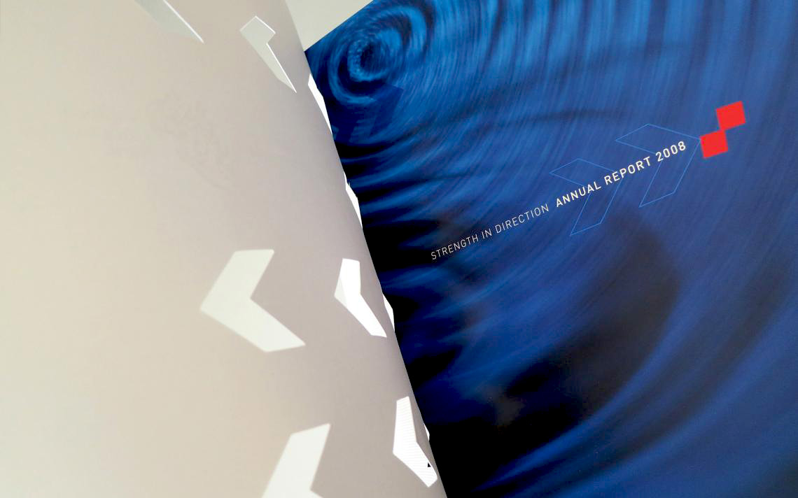 the white die-cut chevron cover of the Khaleej Commercial Bank 2008 Annual Report being lifted open to reveal a striking inner page. This page features a vibrant, swirling deep blue background pattern overlaid with the title text "STRENGTH IN DIRECTION ANNUAL REPORT 2008," a minimalist chevron outline, and two small, solid red accent squares.