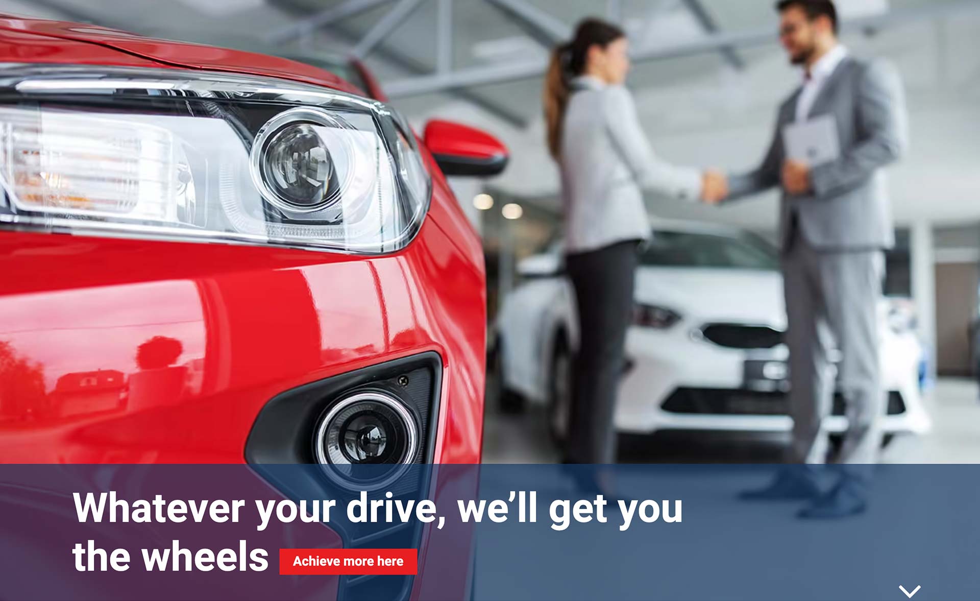 A close-up of a vibrant red car's headlight and front bumper dominates the left foreground, while a blurred background shows a man and a woman in business attire shaking hands in a car dealership next to a white car. The bottom of the image features a blue banner with the text "Whatever your drive, we’ll get you the wheels" and a small red button that reads "Achieve more here".